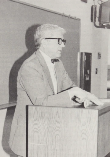 Charles Ares speaking in front of a classroom podium.