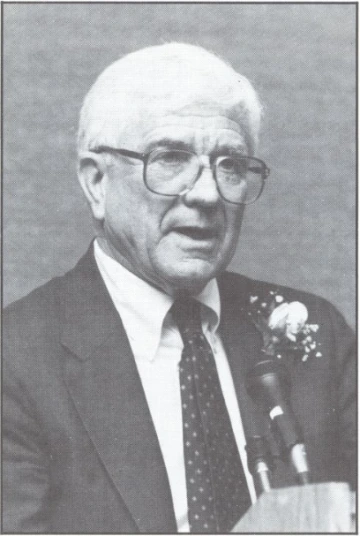 Charles Ares speaking into a microphone at his retirement party.