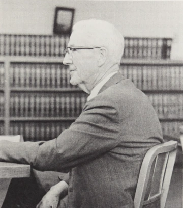 Dean John D. Lyons sitting in a chair in the law library.
