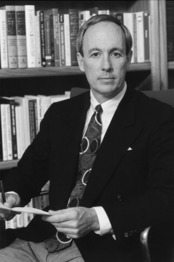 Portrait of E. Thomas Sullivan seated with a document and pen in hand.